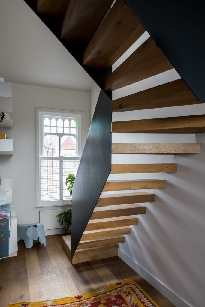 Image of Queen's Park House, North West London, includes a black steel and timber stair to the attic room of a Victorian terrace house 