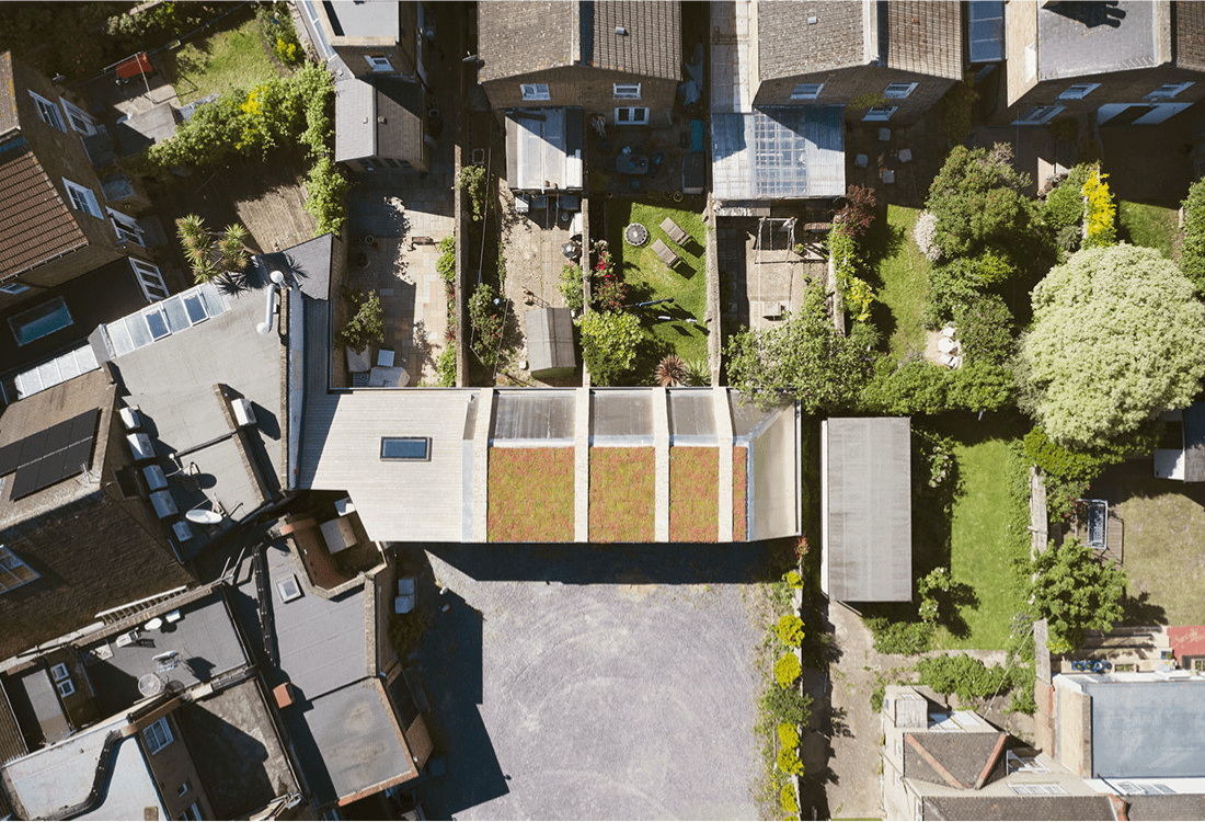 Aerial view of modern sustainable architecture in an urban setting, showcasing eco-friendly features such as green roofs integrated into residential structures. The design emphasises harmony with nature, maximising green space and reflecting a commitment to sustainable, future-oriented urban planning.